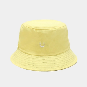 Detailed view of smiley face embroidery on light yellow cotton bucket hat brim