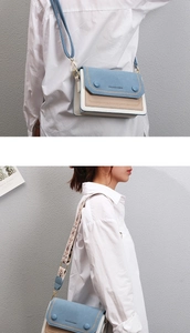 Detail of blue and beige contrast crossbody bag featuring a wide bohemian strap