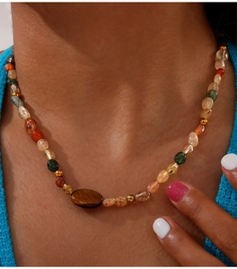 Detail of bohemian beaded necklace with natural tiger eye stones and gold accents