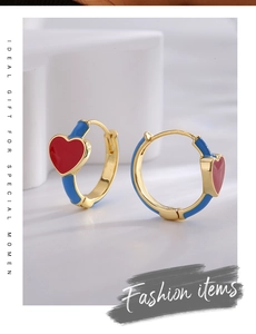 Detail view of heart-shaped hoop earrings with blue and red enamel on gold metal
