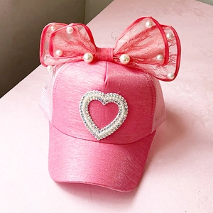 Detailed view of pink girls baseball cap with lace bow, pearls, and rhinestone heart