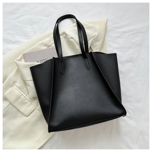 Overhead view of a minimalist black leather tote bag on a blazer for business casual style