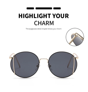 Detail view of round metal sunglasses featuring golden frames and dark grey lenses