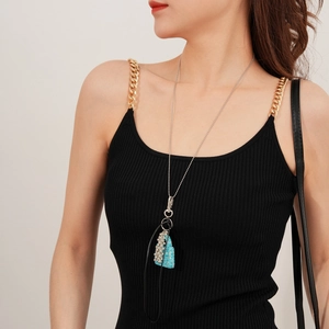 Détail du collier avec pendentif mini sac en strass bleus sur chaîne argentée porté par mannequin