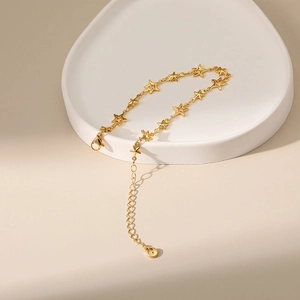 Elegant 18K gold plated bracelet with hollow star pendants on a white display tray
