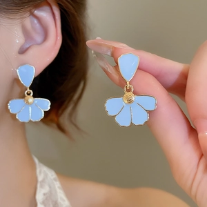 Close-up of blue floral drop earrings with gold trim worn to show elegant product detail