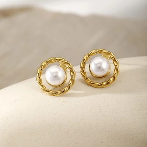 Macro shot of gold twist rope frame earrings with central white round pearl detail
