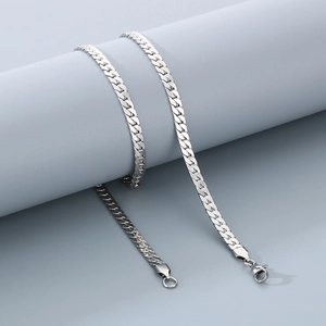 Close-up of a silver flat Cuban link necklace with lobster clasp on a grey cylinder