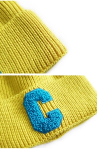 Detail of yellow ribbed knit hat featuring a blue C-letter towel embroidery patch