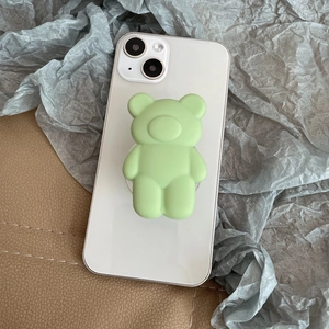Detail of a matte light green bear phone socket grip on a white smartphone back