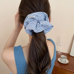 Close-up of blue striped fabric scrunchie on a ponytail with premium AYdrea brand label