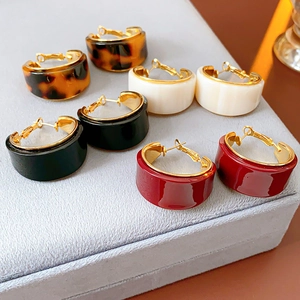 Detail of four pairs of C-shaped resin earrings in tortoise, white, black, and red colors