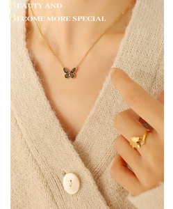 Detail showing gold butterfly necklace with black enamel inlay and matching open ring
