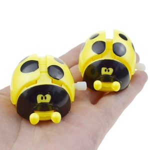 Pair of yellow and black wind-up ladybug clockwork toys held in a hand for scale