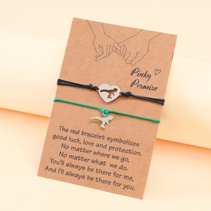Detail view of woven couple bracelets with dinosaur pendants on pinky promise card