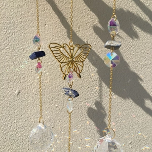 Detailed suncatcher with crystal ball and butterfly casting rainbow light on wall