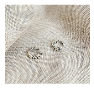 Detail of vintage silver hoop earrings with smile face engraving on burlap background