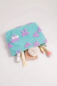 Detail of plush turquoise makeup bag with purple teddy bear applique and soft texture
