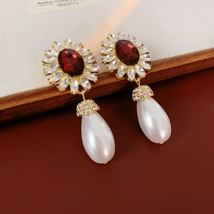 Macro shot of vintage floral gold earrings with ruby-red gemstones and drop pearls