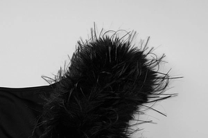 Detailed close-up of fluffy black feather trim on an elegant evening gown shoulder
