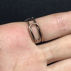 Close-up of vintage bronze double-band ring with oval connector on a finger