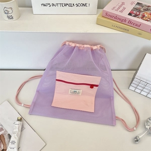 Détail d'un sac à dos violet en maille avec une poche frontale rose à fermeture