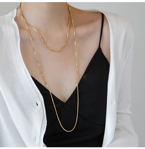 Long gold snake chain necklace in titanium steel on model with stylish layered look