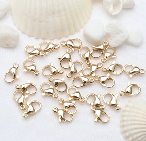 Polished 14k gold lobster clasps for DIY jewelry making laid on a white texture