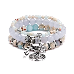 Detailed shot of bohemian tree of life and feather charms on beaded gemstone bracelets