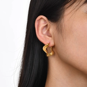 Vintage gold striped twisted hoop earrings with wavy texture on model's ear