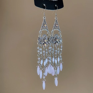 Detail of silver hollowed-out bohemian earrings with pink beaded teardrop tassels