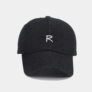 Detailed texture of black denim baseball cap featuring a white embroidered letter R logo