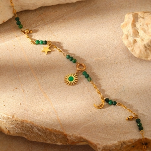Close-up of gold chain with green faceted beads and celestial sun moon star charms