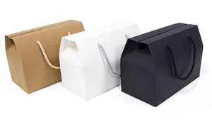 Handheld gift boxes in brown, white, and black with woven handles and folding lids