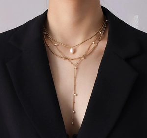 Detailed view of layered gold Y-necklace featuring baroque pearls and long elegant tassels