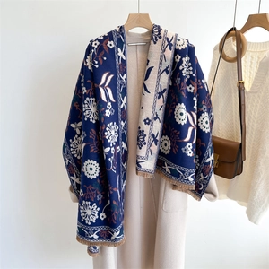 Detail view of a blue and beige floral scarf with woven texture and tassel edges on a coat
