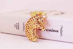 Detailed close-up of a gold hollow unicorn keychain with red gem accent on a white book