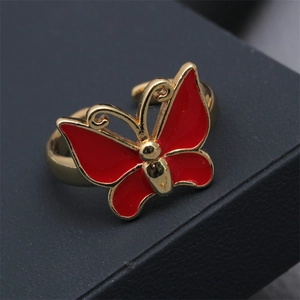 Close-up of red enamel butterfly ring on a dark textured gift box edge