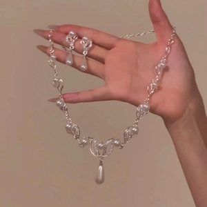 Detail of silver leaf and pearl necklace set held in hand for a vintage court look