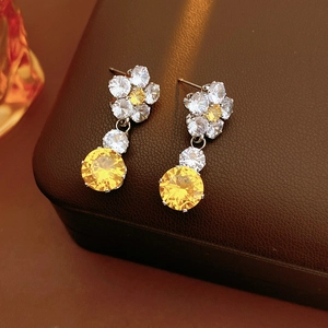 Macro view of luxurious flower drop earrings with yellow zircons and silver finish
