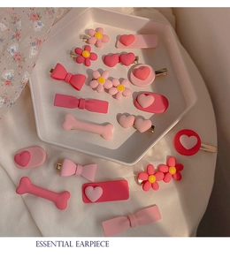 Detailed close-up of pink resin hair clips with flower, heart, and bow shapes on a tray