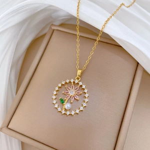 Detail of round floral pendant with pink gem and pearl in a jewelry box