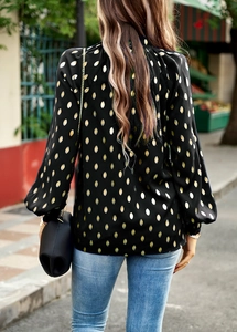 Rear view of women's black blouse with gold polka dots and lantern sleeves in street style