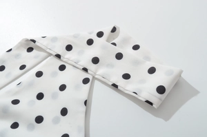 Detailansicht eines weißen Neckholder-Minikleids aus Chiffon mit schwarzem Punktmuster