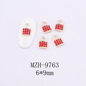 Vue macro de breloques à ongles cadenas cœur rouge et strass dorés 6x9mm