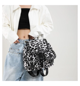 Detailed side view of leopard print backpack with metal studs and leather straps