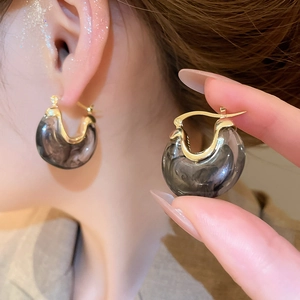 Détail de boucles d'oreilles vintage en U en résine marbrée grise avec accents dorés