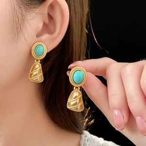 Détail de boucles d'oreilles dorées vintage avec incrustation de turquoise