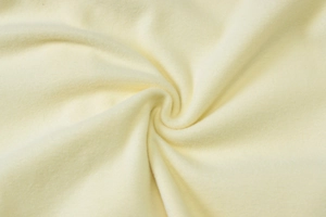 Detailed macro view of soft pale yellow knitted cotton fabric texture and flexible weave