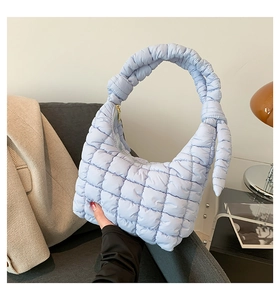 Detail of light blue quilted puffer bag with soft knots and padded handle texture